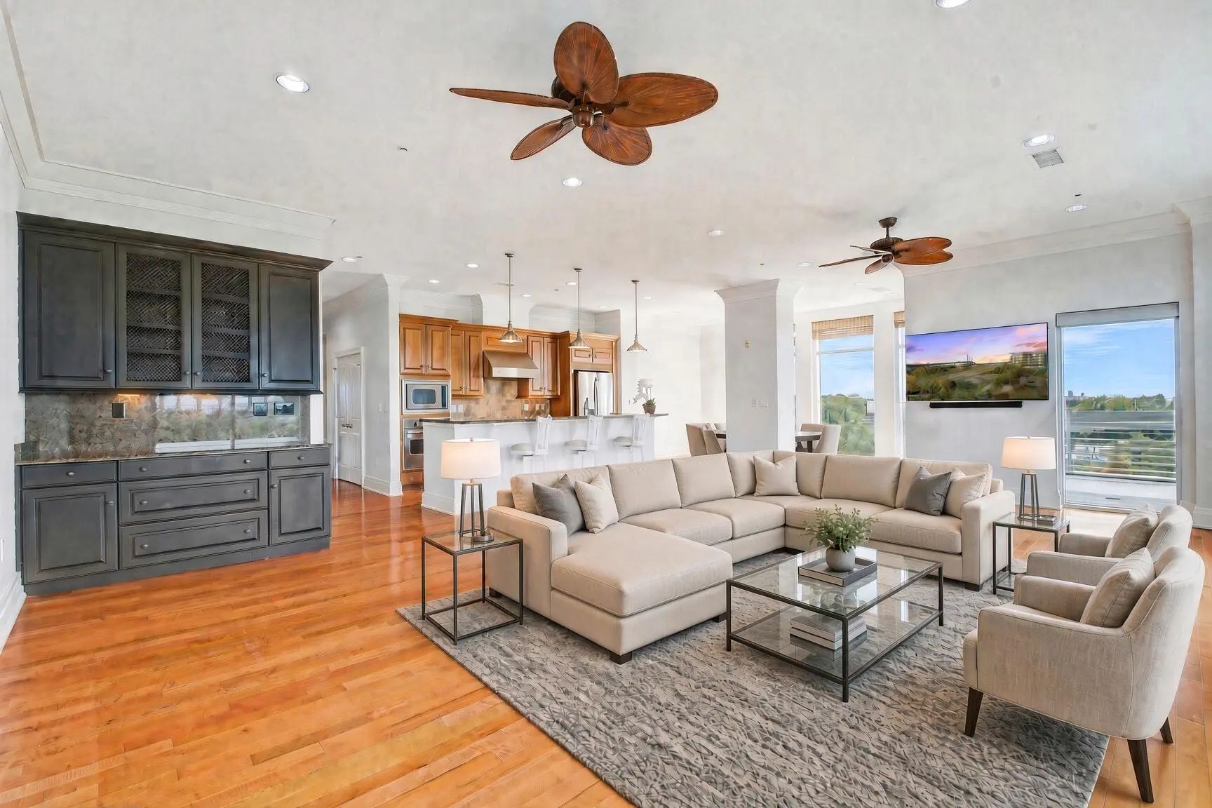 Open great room with wood floors, floor-to-ceiling windows and the kitchen island beyond in unit 241 at The Tides, Mount Pleasant