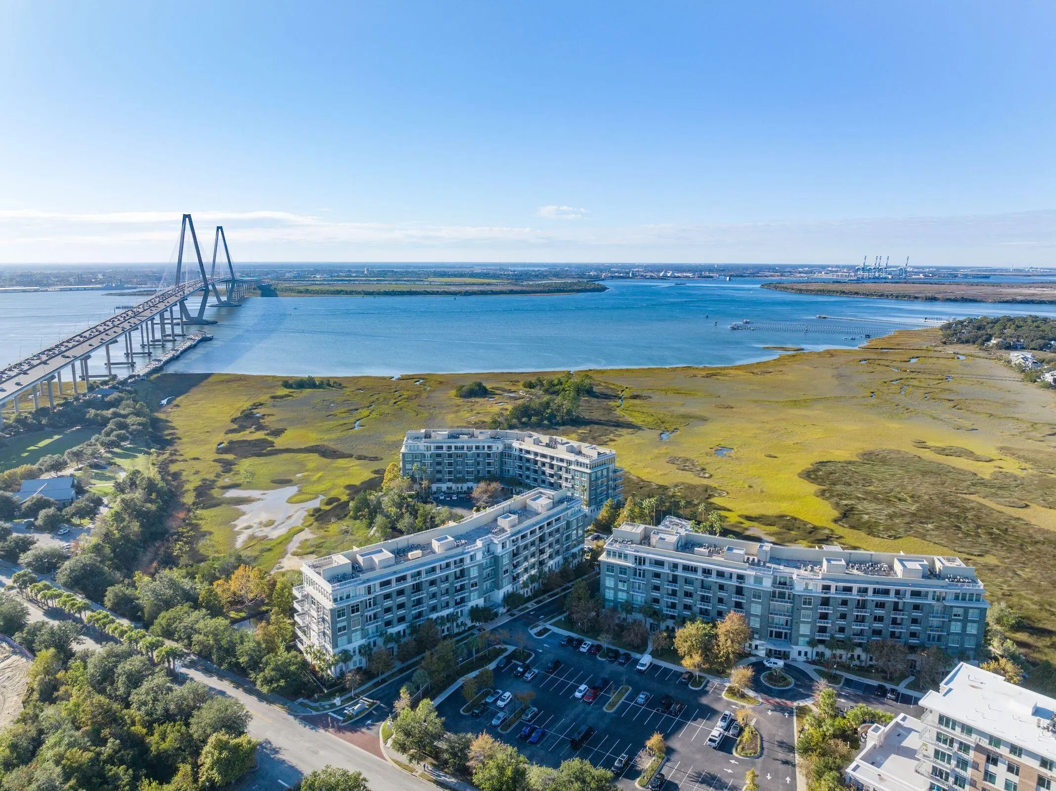 Aerial view of The Tides condominiums at the edge of the marsh with the Ravenel Bridge and Wando River beyond in Mount Pleasant, SC
