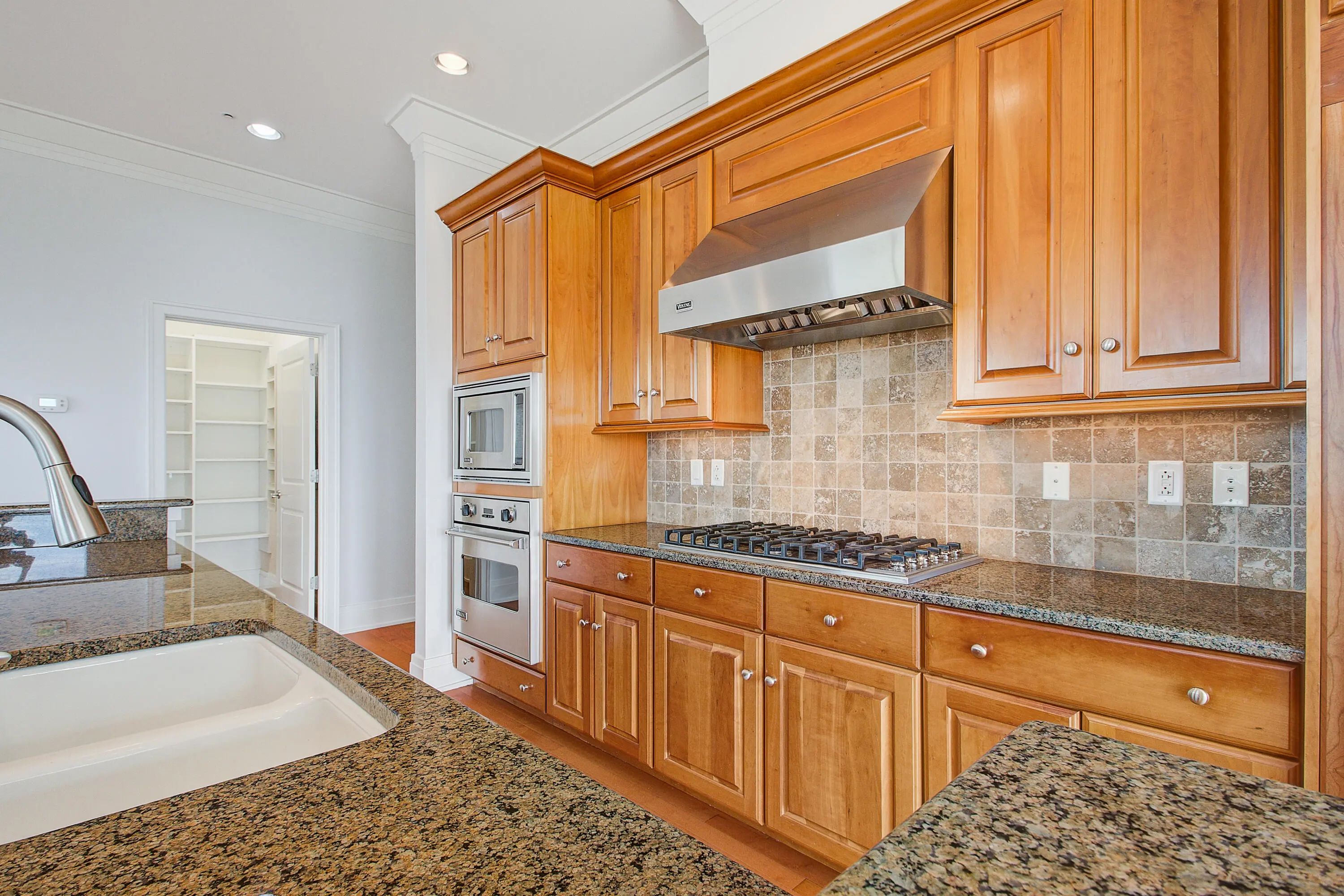 Kitchen with wood cabinetry, granite counters, cooktop and stainless hood at 241 Cooper River Drive, Mount Pleasant, SC