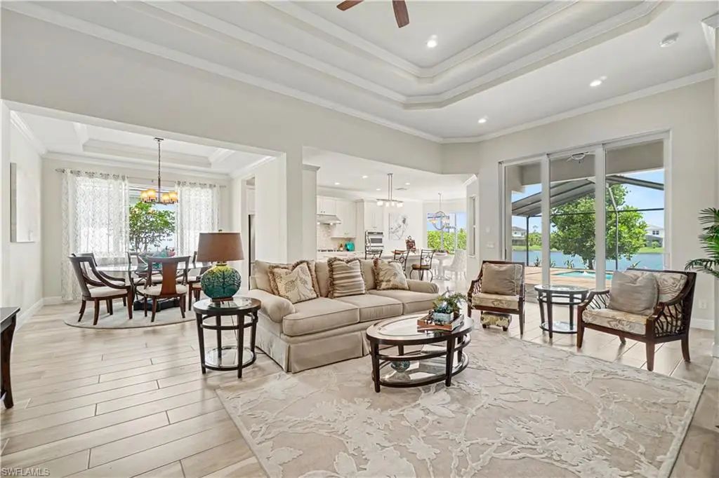 Great room with tray ceiling and lake views through sliding glass doors at 9062 Montserrat Drive in Naples