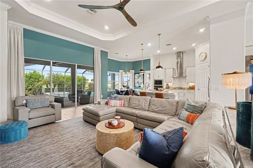 Great room at 15880 Talon Terrace with tray ceiling, tile floors and sliding glass doors open to the screened lanai and lake view