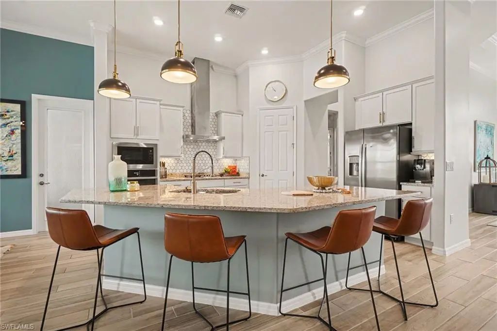Kitchen at 15880 Talon Terrace in Babcock National with a granite island, leather counter stools, white custom cabinetry and pendant lighting